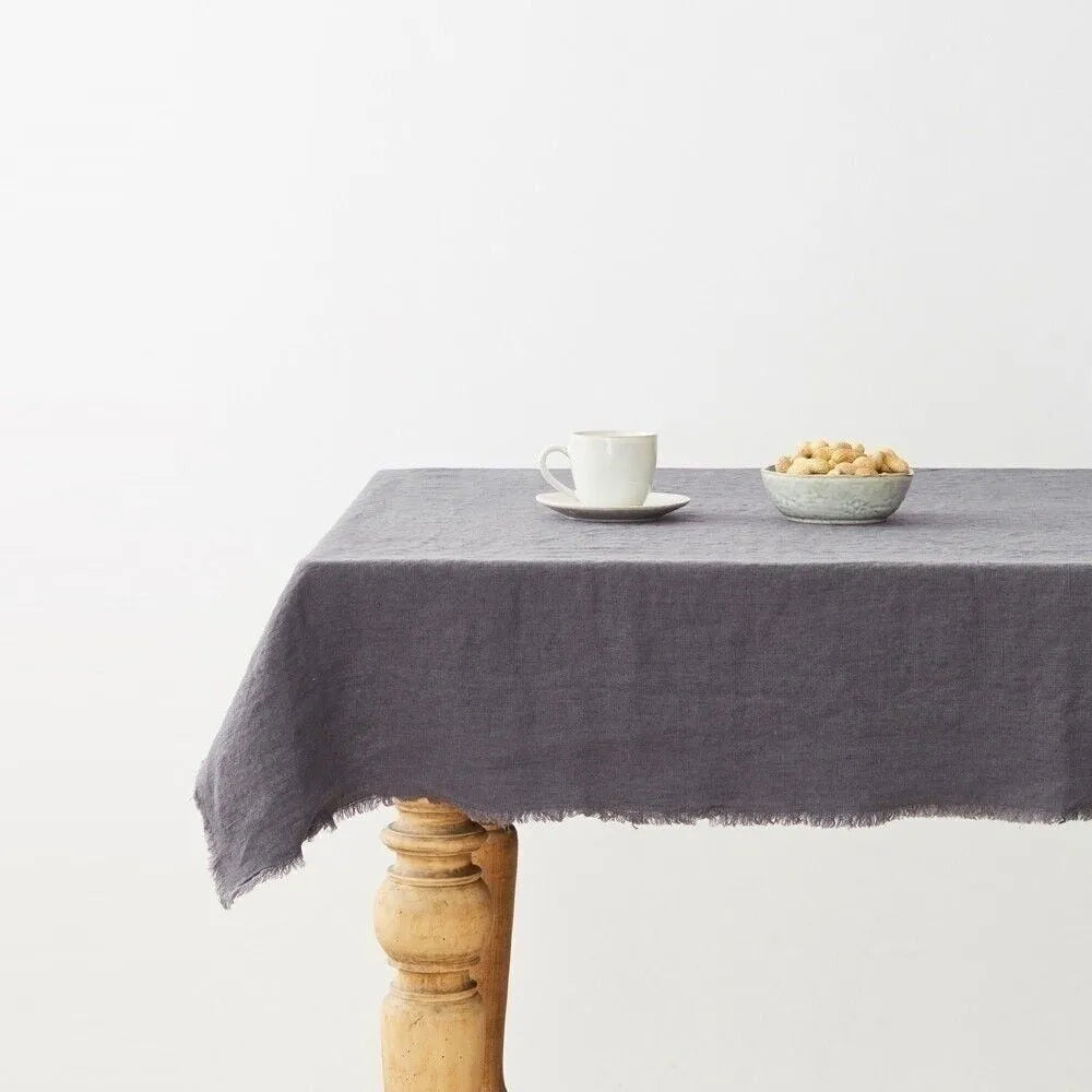 Gray tablecloth on a wooden table with a white mug and bowl against a white background