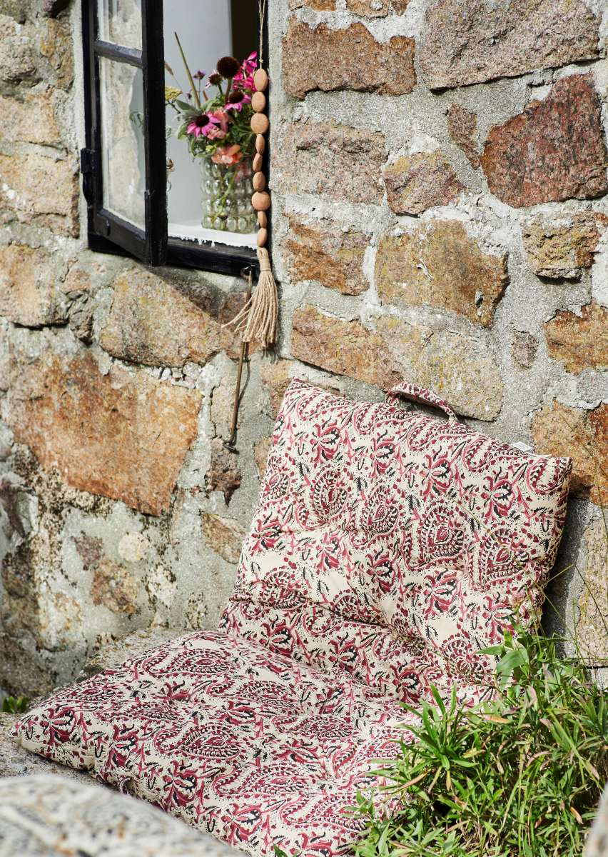 Floral block print mattress leaned up against an old cottage wall on a sunny day