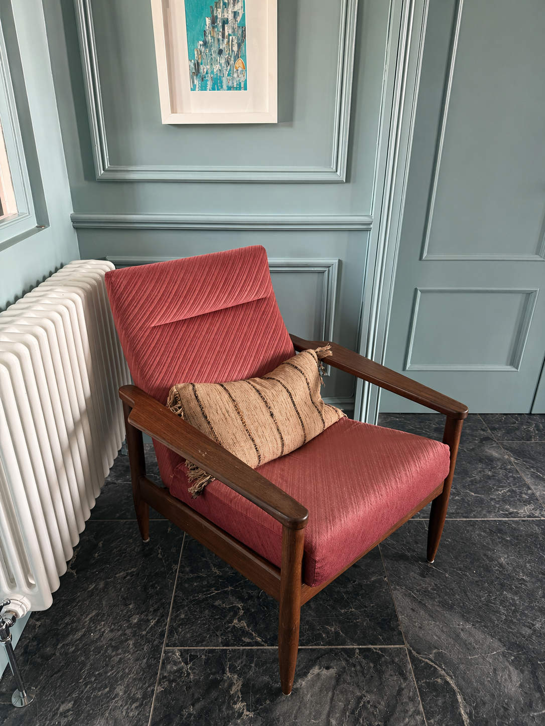Rustic grain sack cushion on dusky pink mid-century armchair in a green blue panelled corner.