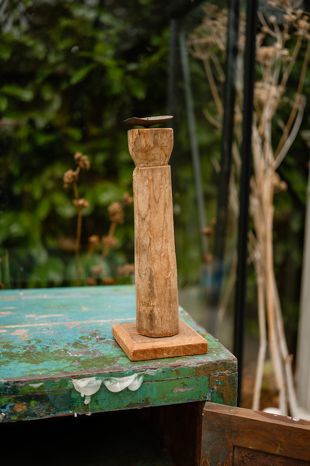 Wooden candle holder on a rustic table with a blurred natural background