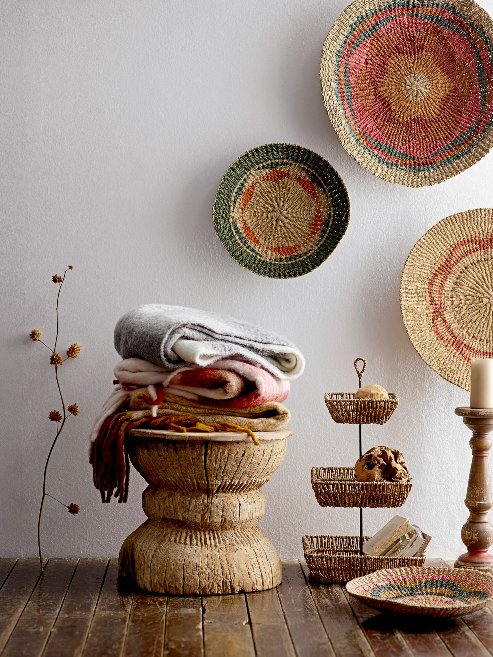 This image features a handcrafted reclaimed wood stool, elegantly designed with a rustic and weathered texture that adds a touch of vintage charm to any space. The stool is prominently displayed with a stack of colorful, patterned baskets and a plush, inviting cushion on top, enhancing its functionality and aesthetic appeal.