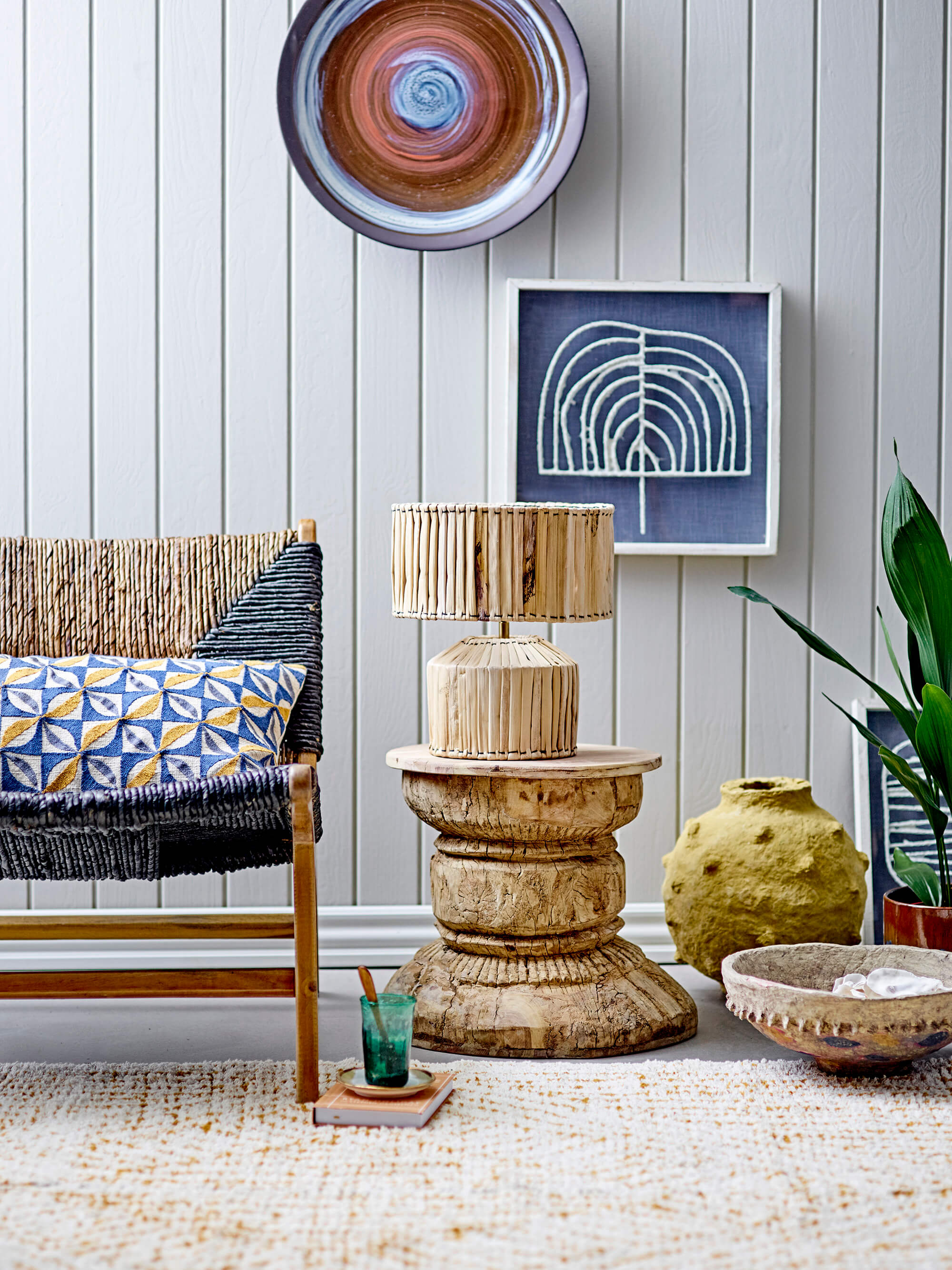 Reclaimed wood stool with rattan lamp against panelled wall and other decorative elements