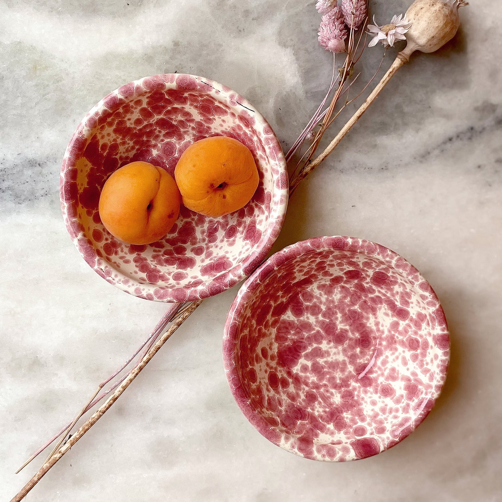 Overhead shot of red splatter mini bowls on white marble surface