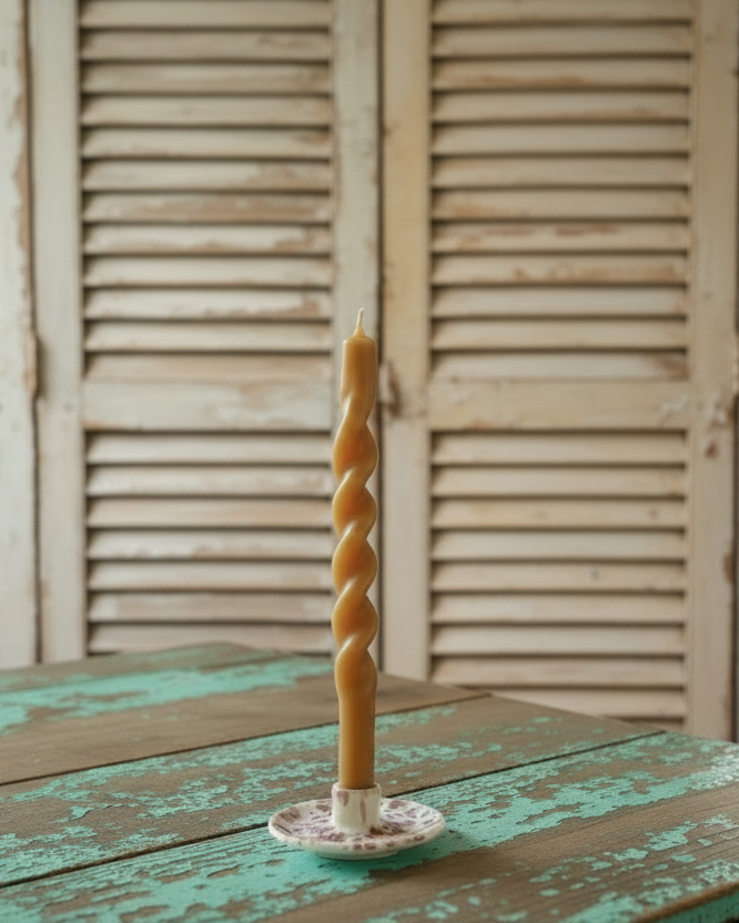 Twisted candle on a wooden table with vintage shutters background