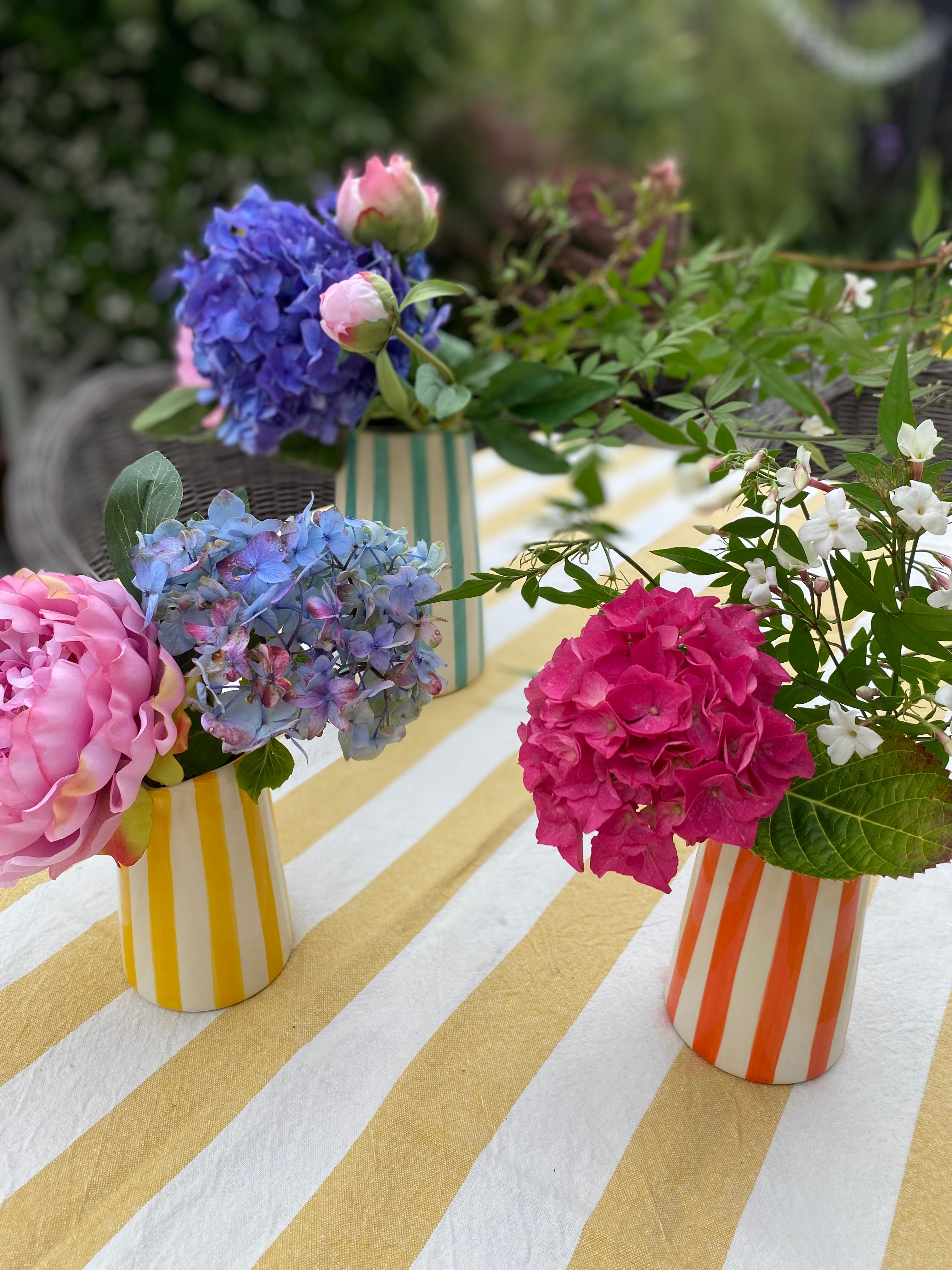 Cluster of striped ceramic jugs on yellow in an  outdoor setting
