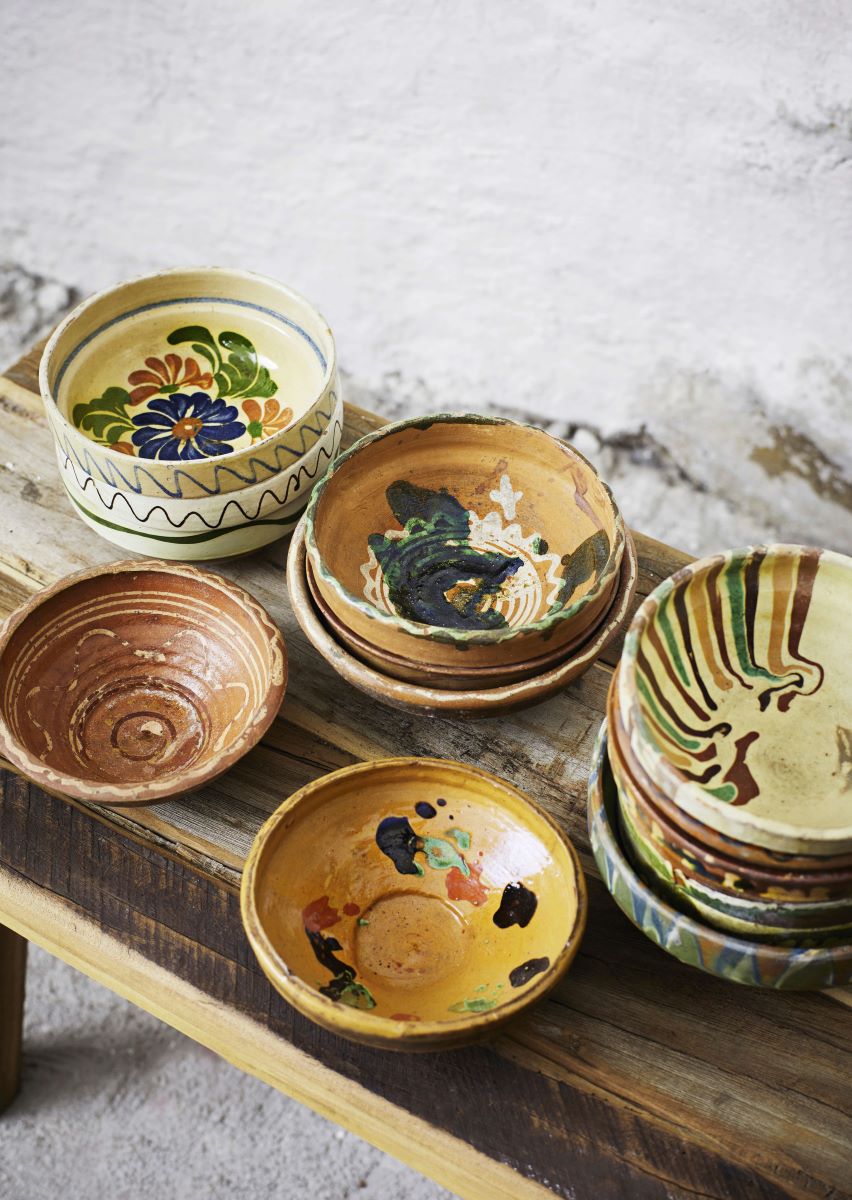 Stacks of handpainted patterned clay bowls on a rustic bench