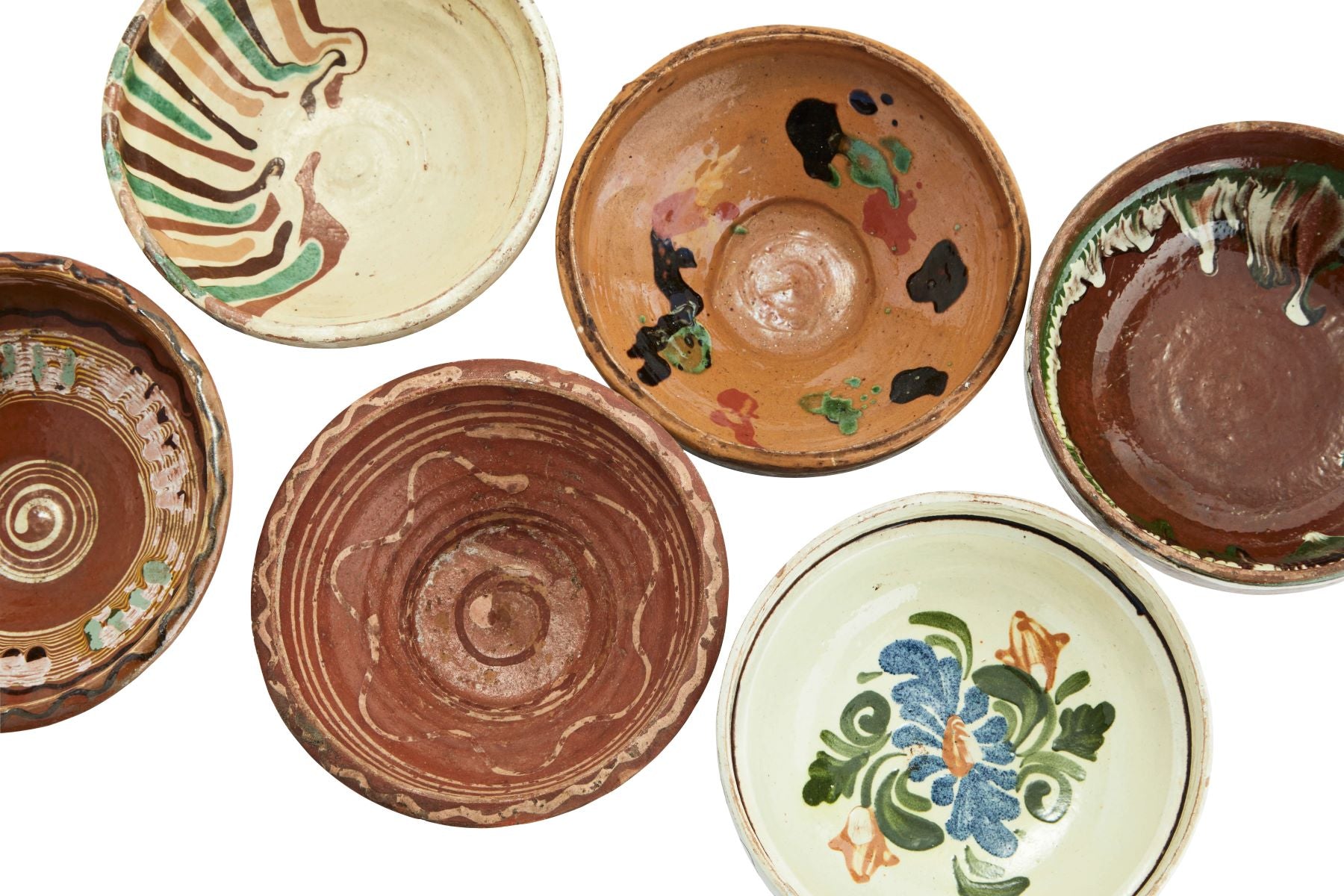 Overhead view of a collection of handpainted vintage clay bowls against white background 