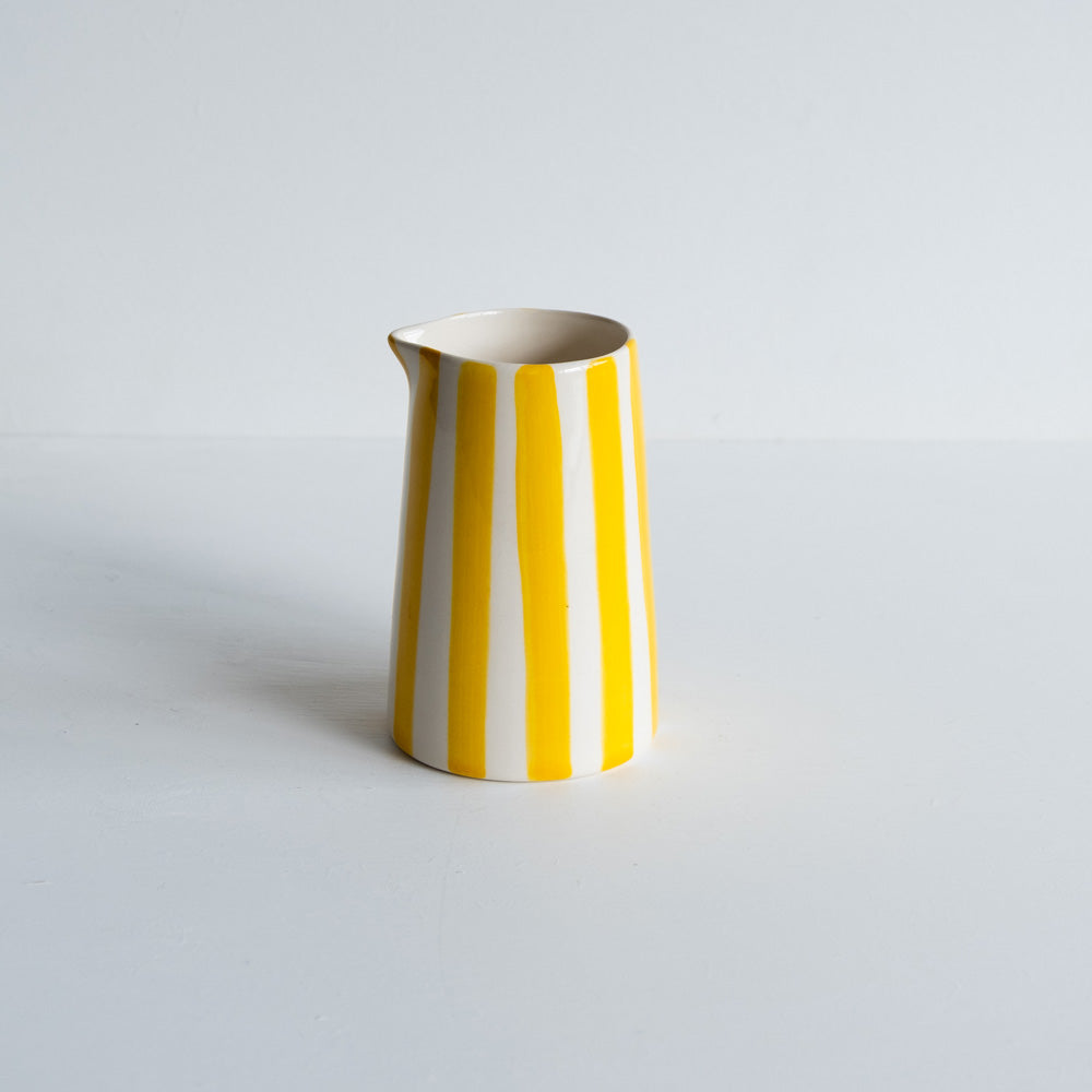 Yellow striped handmade ceramic jug on white background