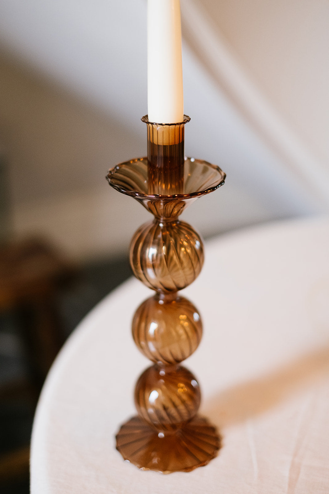 Brown glass candleholder with stacked design against cream background