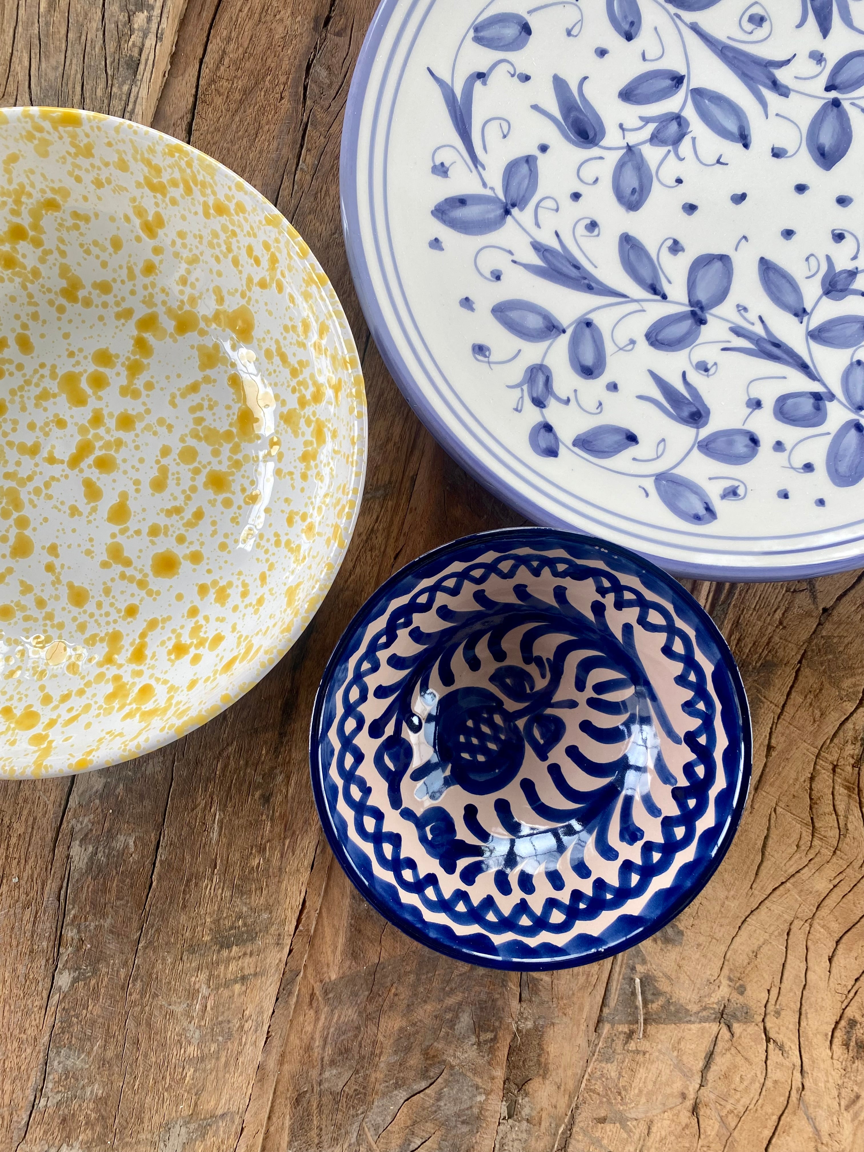 Overhead view of Spanish bowl with blue motif, Italian splatter yellow bowl, handpainted blue italian plate