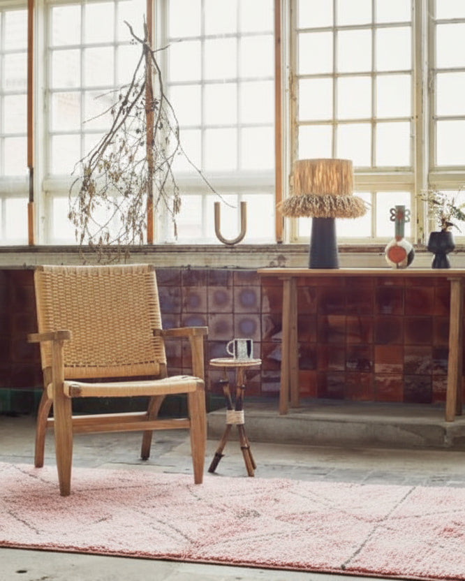 This image features a textured black lamp with a raffia shade, adding a bohemian flair to the decor. The lamp is crafted from terracotta with a sleek black finish, complemented by a playful, textured raffia shade.